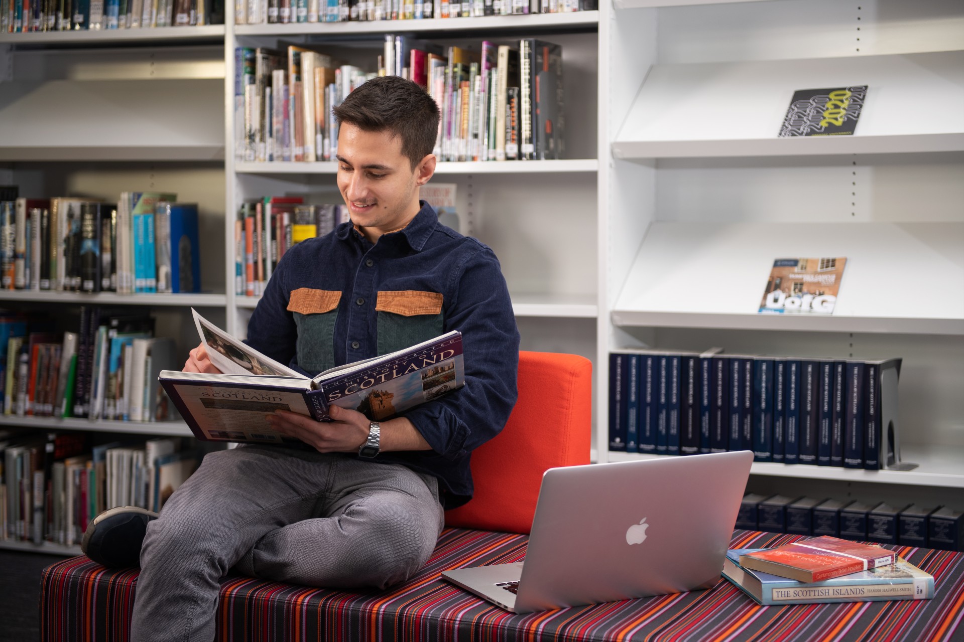 Young male student reading a book in the library. 