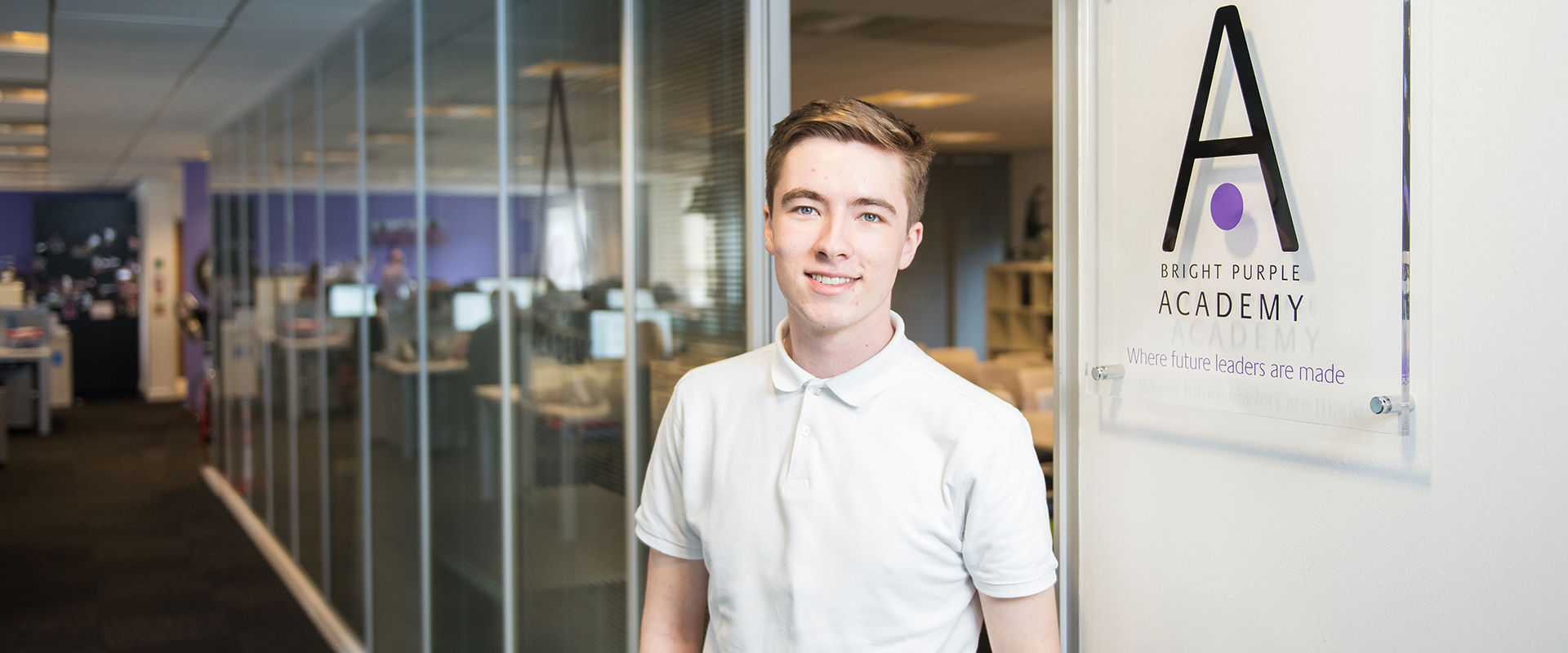 Young student standing next to the sign in an office on their work placement.