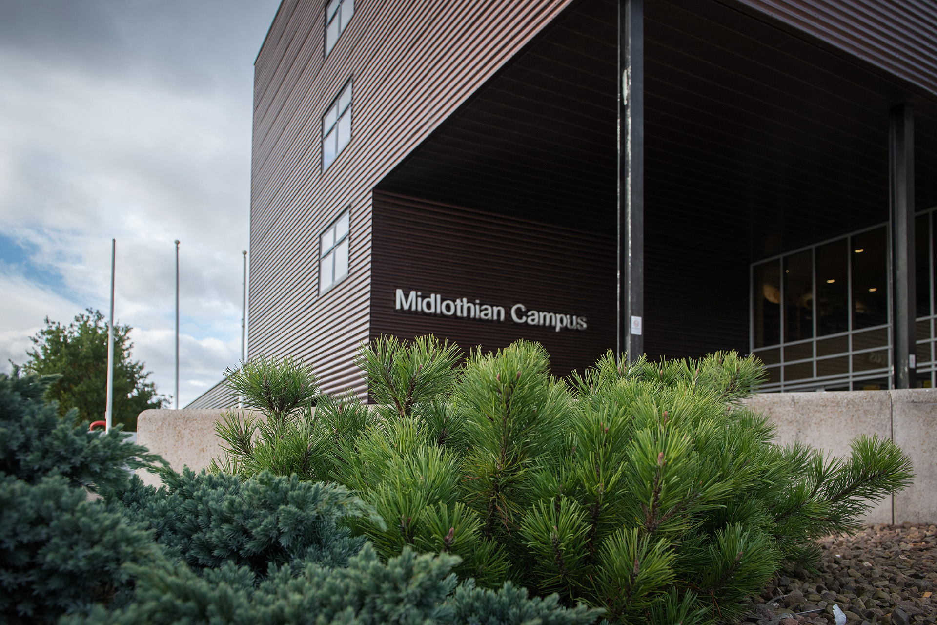 Shrubbery outside the Midlothian campus building, with the campus sign on the building.