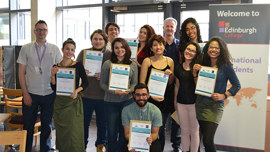 A diverse group of students proudly holds certificates, celebrating their achievements in an indoor setting.