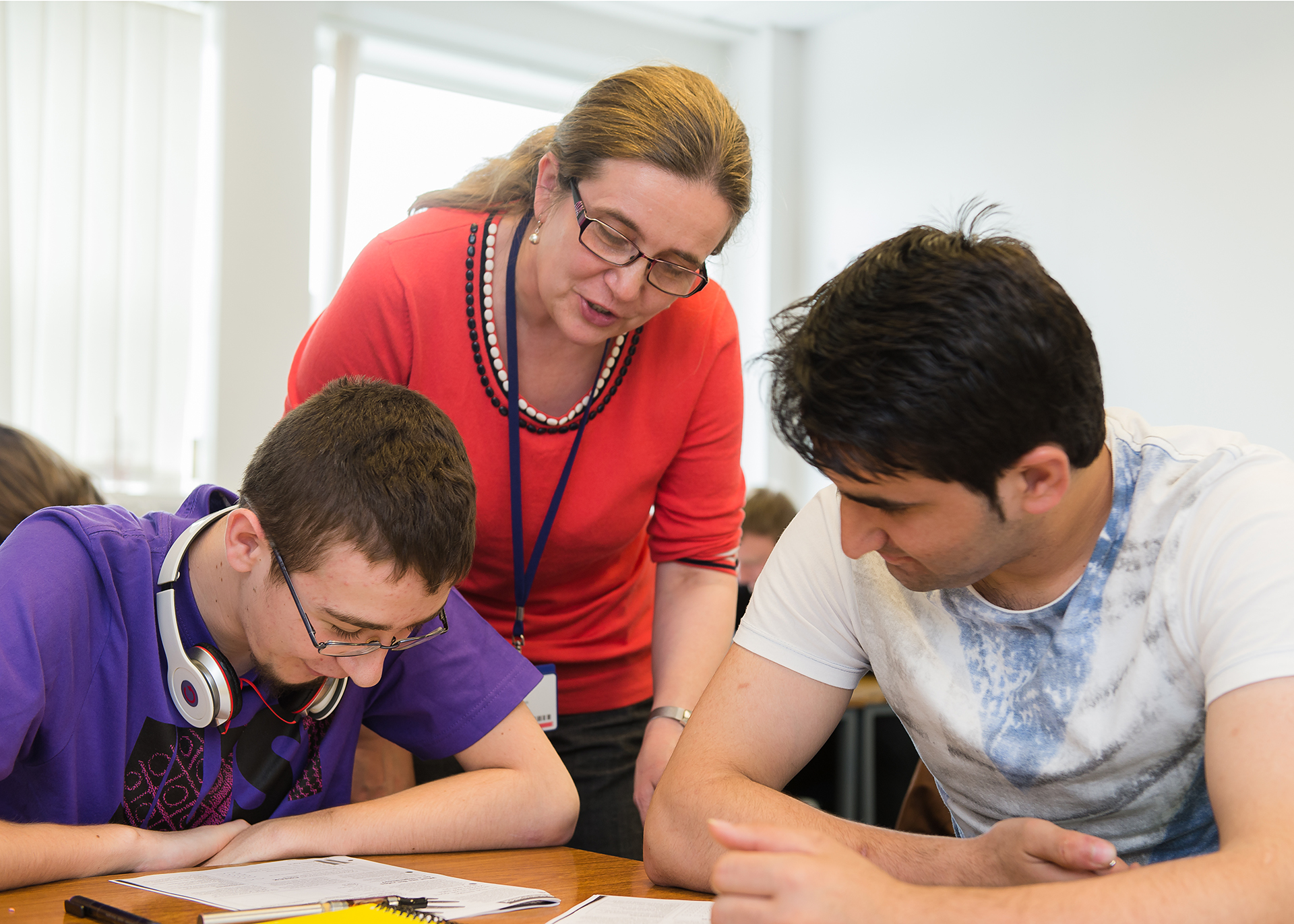 Lecturer supporting two students who are working in a classroom.