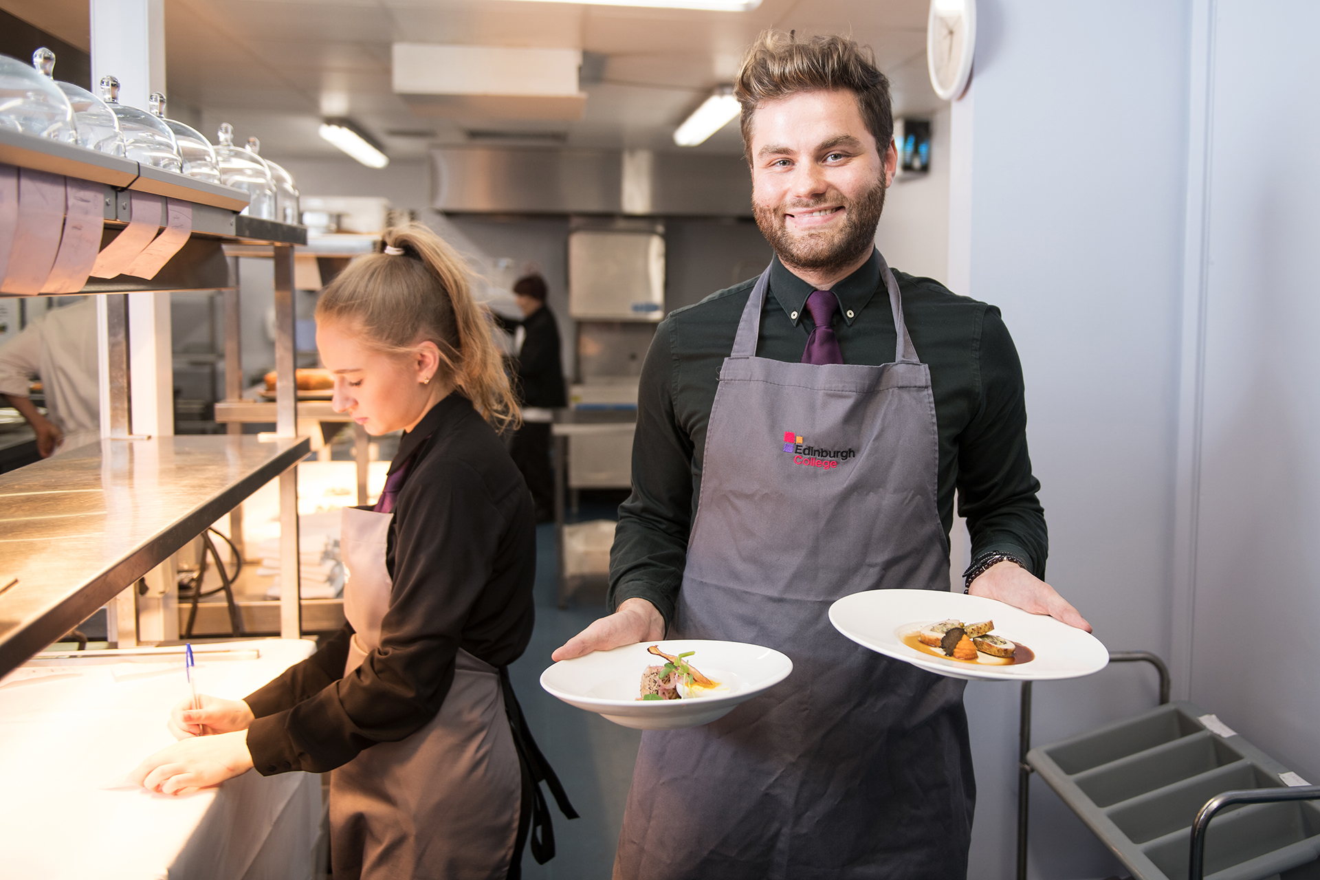Hospitality student holding two plates ready to be served to customers.