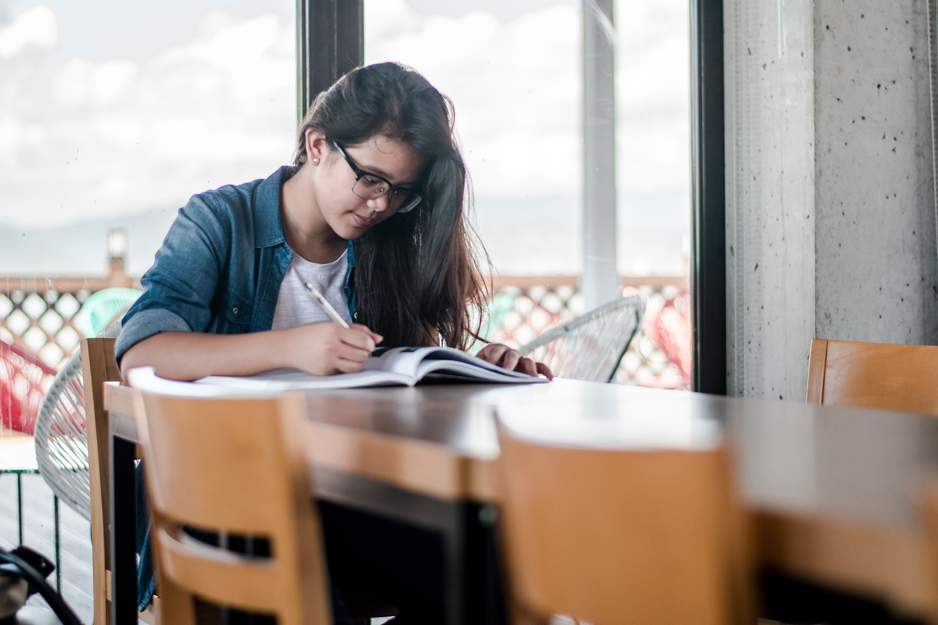 Young student looking through a textbook at a table. 